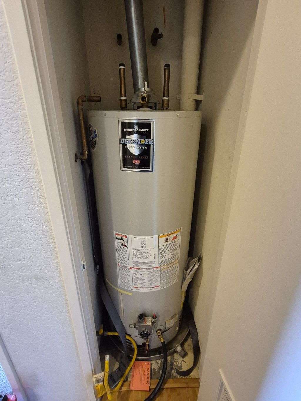 Existing Oceanside water heater during removal, with upper water connections already disconnected.