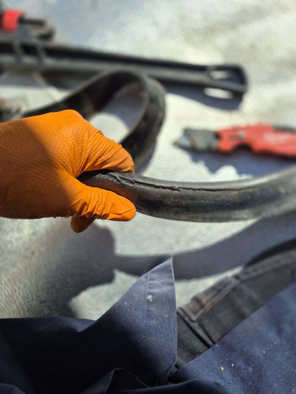 Removed storage-tank gasket held by a gloved technician, showing visible damage along the rubber.